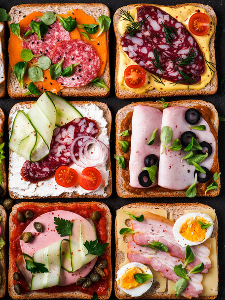 Set van acht verschillende sandwiches met vlees in vierkante vorm. Bovenaanzicht of flat lay. Assortiment vleestoast op zwarte achtergrond. Idee, creatief concept voor worstenmaker - Foto, afbeelding