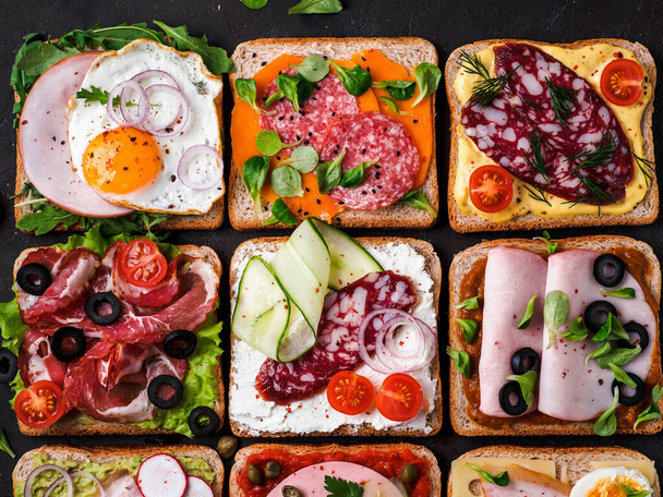Set of eight different sandwiches with meat in square shape. Top view or flat lay. Assortment meat toasts on black background. Idea, creative concept for sausage maker - Foto, afbeelding