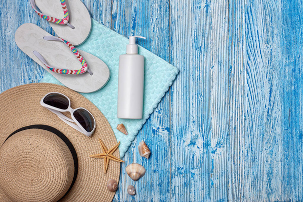 ビーチアクセサリー:青い木製の背景に白い女性のフリップフロップ、わら帽子、サングラス、日焼け止め。コピースペース付きのトップビュー。海の休暇と旅行の概念。夏の背景、 uvからの保護 - 写真・画像