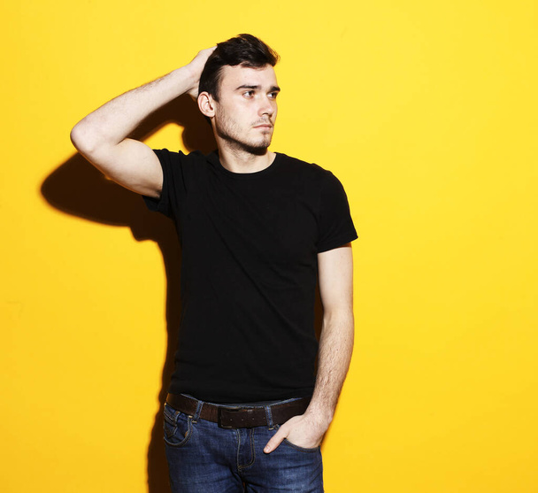 Young handsome fashionable male model standing against yellow background - Foto, Imagem