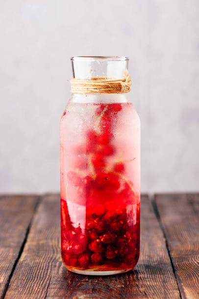 Red currant infused water with ice in glass bottle - Foto, immagini