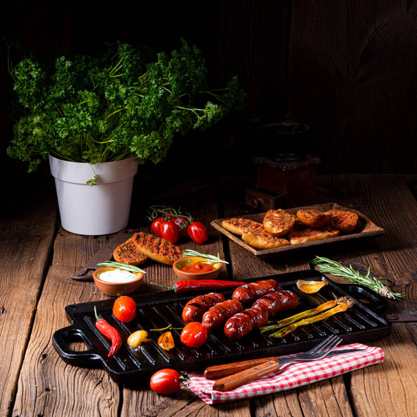 grilled sausages with vegetables and spices on a wooden table - Fotoğraf, Görsel