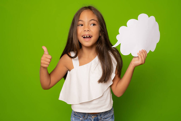 Portrét roztomilé veselá dívka drží papírový mrak s palcem nahoru kopírovat prostor izolovaný přes zelené pozadí - Fotografie, Obrázek