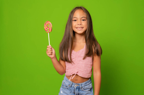 Gelukkig lachend meisje met suikerlolly. Meisjesportret met grote snoep. Suiker voor kinderen. - Foto, afbeelding