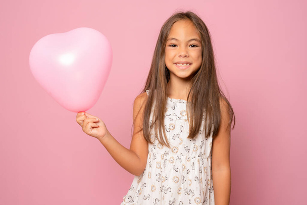 Piękna dziewczynka z pastelowym różowym powietrzem balon izolowane na różowym tle. - Zdjęcie, obraz