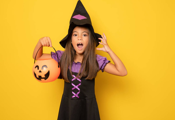 Beautiful little girl in Halloween costume isolated over yellow background.Halloween, carnival, childhood, fairytale theme. - Zdjęcie, obraz