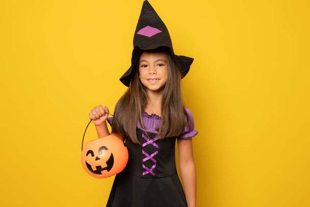 Piękna dziewczynka w kostium Halloween izolowane na żółtym tle.Halloween, karnawał, dzieciństwo, motyw bajki. - Zdjęcie, obraz