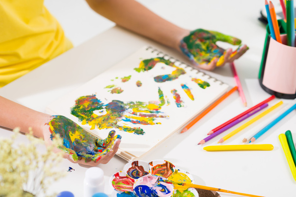 Menina fazendo impressões de mão multicoloridas
 - Foto, Imagem
