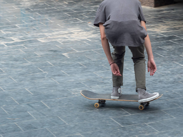 Vrijetijdsbesteding. Sportieve levensstijl. Jonge skateboarder in het publieke park. Extreme sporten zijn erg populair onder de jeugd. - Foto, afbeelding
