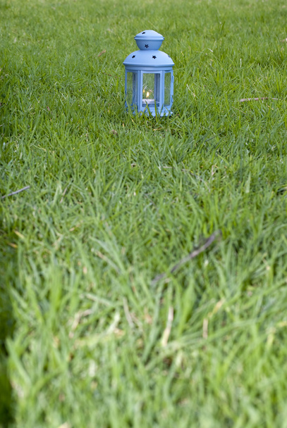 Lanterne bleue, avec bougie allumée à l'intérieur, sur herbe verte
  - Photo, image