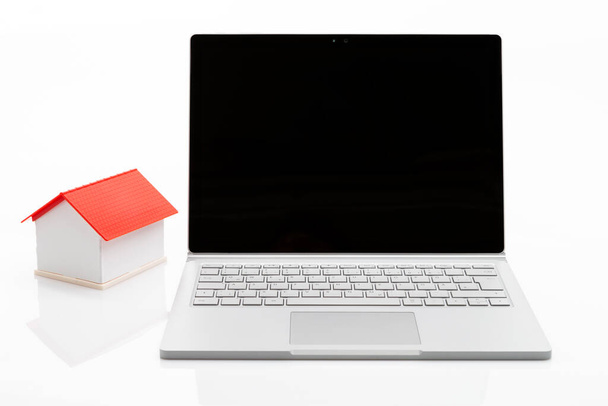 Image shows a Laptop with a house isolated on white - Фото, изображение
