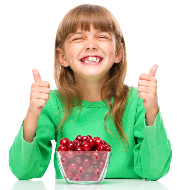 Cute girl is eating cherries showing thumb up sigh - Fotografie, Obrázek