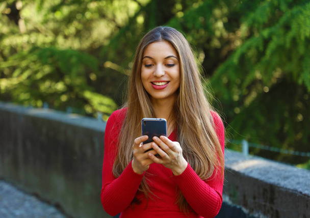 Beautiful young woman using smart phone in the park - 写真・画像