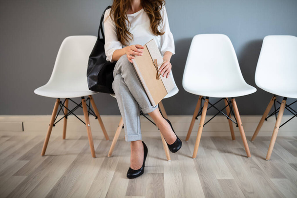 Young Businesswoman Holding Folder While Sitting On Chair Waiting For Job Interview - Photo, Image