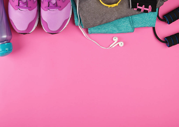 pink women's sneakers, a bottle of water, gloves and a jump rope for sports on a pink background, top view, copy space, flat lay - Fotoğraf, Görsel