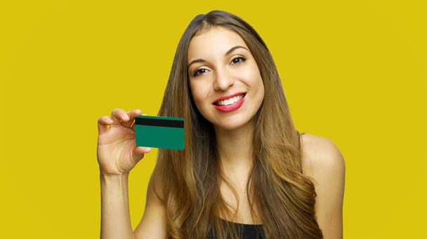 Happy woman hold credit card isolated on yellow background - Foto, Imagen