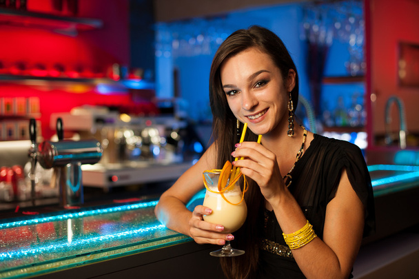 Девушка выпивает коктейль в ночном клубе
 - Фото, изображение