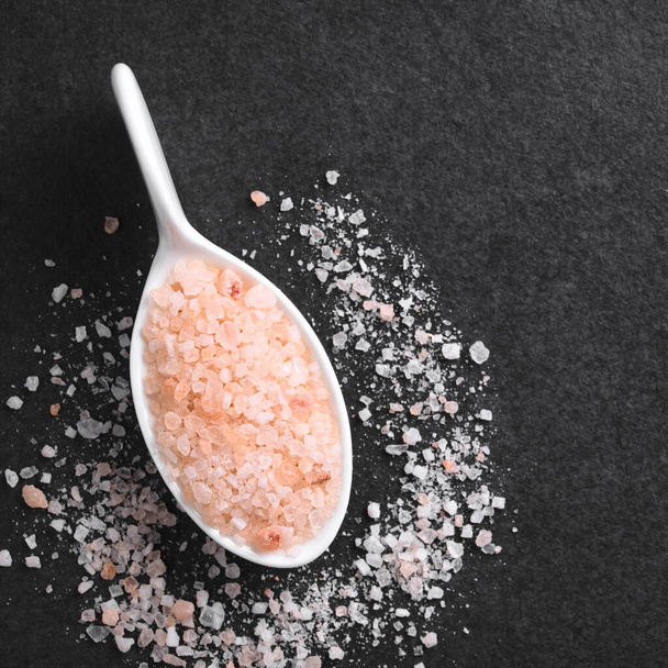 Coarse pink Himalayan salt on small spoon, photographed overhead on slate (Selective Focus, Focus on the salt on the spoon) - Foto, Imagen