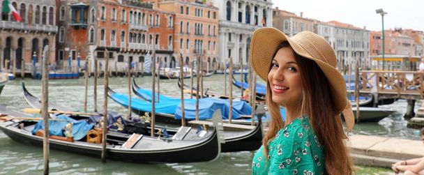 Holidays in Venice! Beautiful woman with straw hat smiling at camera with Venice Grand Canal, gondolas and palaces on the background. Panoramic banner view. - Фото, изображение