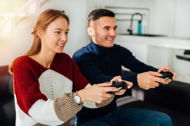 Young happy friends, guy and girl, playing video games, excited, sitting on couch at home. - Foto, Bild
