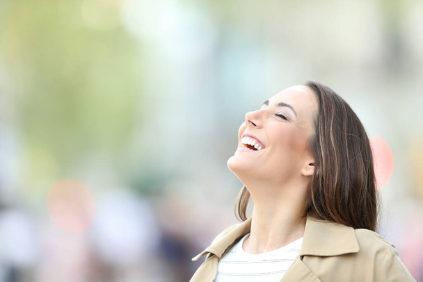 Happy woman breathing fresh air in the street - Photo, image