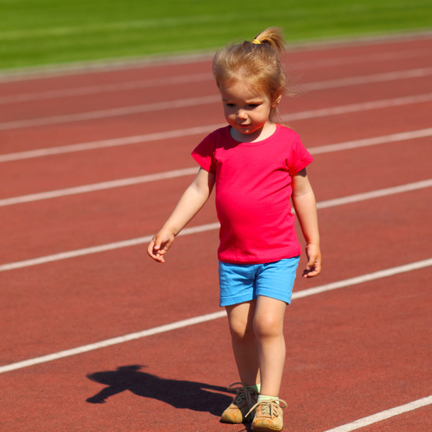 Маленька дівчинка біжить на стадіоні
 - Фото, зображення