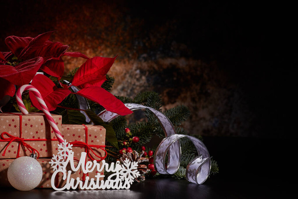 Christmas decoration with Red Poinsettia flowers (Euphorbia Pulcherrima), fir branch and gift boxes on a dark background.  Christmas background with copy space. Greeting card. - Fotoğraf, Görsel