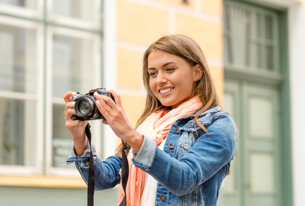 улыбающаяся девушка с дигиральной фотокамерой в городе
 - Фото, изображение