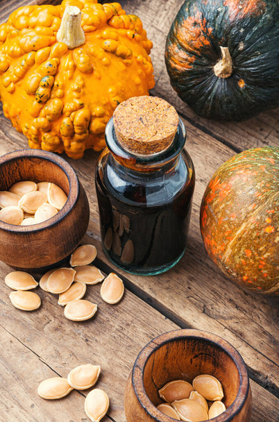 Pumpkin and pumpkin seed oil on wooden table - Фото, изображение