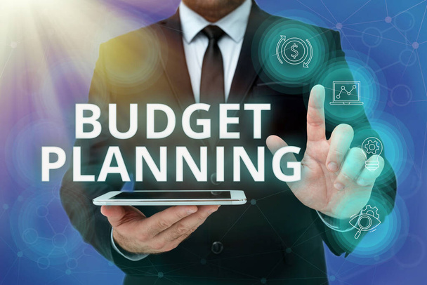 Tekst pokazujący inspirację Planowanie budżetu. Business idea procesu budowy budżetu, a następnie wykorzystanie go Man In Office Uniform Standing Pressing Virtual Button Holding Tablet. - Zdjęcie, obraz