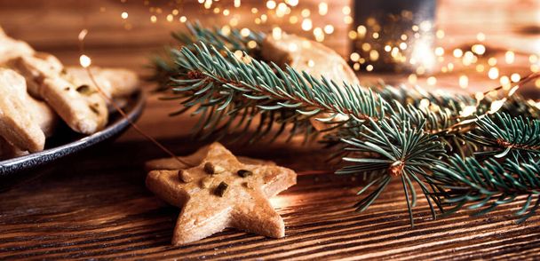 Tasty homemade christmas cookies with festive golden lights on rustic wood - Фото, изображение