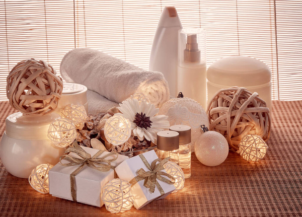 Spa still life with cosmetic creams,  towel, gift boxes and Christmas ornaments standing on bamboo mat. New Year and Christmas Healthy lifestyle, body care, Spa treatment and relaxation concept - Foto, immagini