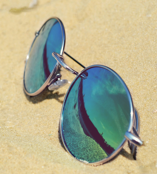 Lunettes de soleil miroir sur sable avec un reflet de la plage
 - Photo, image