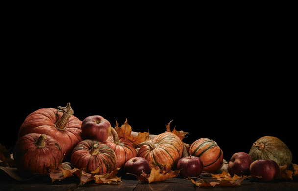 Festive autumn still life  with pumpkins, red apples and leaves on dark wooden table on black background with copy space. Concept of autumn harvest, happy Thanksgiving  day or Halloween. - Photo, image