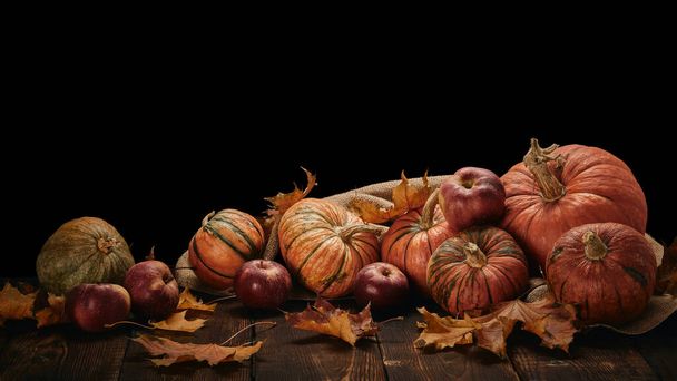 Festive autumn still life  with pumpkins, red apples and leaves on dark wooden table on black background with copy space. Concept of autumn harvest, happy Thanksgiving  day or Halloween. - Foto, Imagem