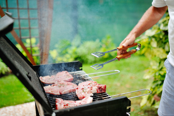 Hombre en la parrilla de barbacoa preparando carne para una fiesta en el jardín
 - Foto, imagen
