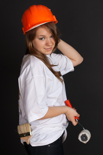 The girl in the orange helmet with a roller in his hand - Foto, Bild