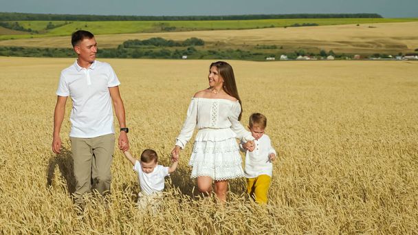 小さな子供を持つ家族は夏に小麦畑を歩く - 写真・画像