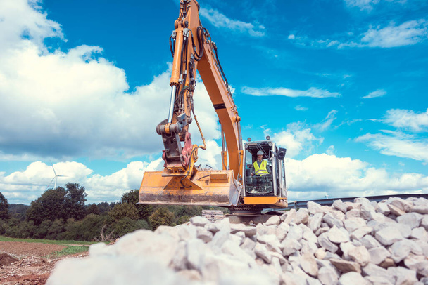 Woman operating an excavator on road works construction site or public works - Photo, image