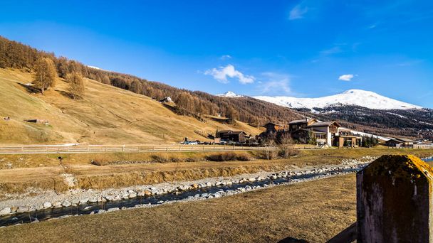Beautiful mountain valley with stream, trees, wooden fence and footpath, Livingo village in background, Italy, Alps - Φωτογραφία, εικόνα
