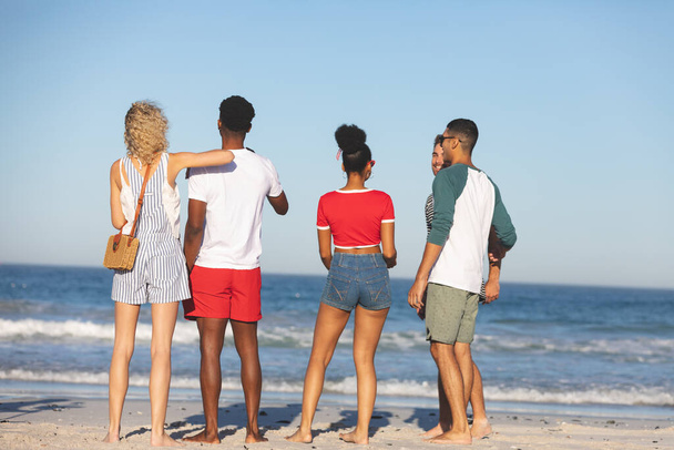 Rear view of diverse friends having fun together on the beach - Fotoğraf, Görsel