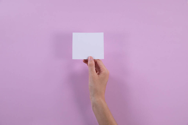 Right hand holding an empty post-it note with a purple background for valentines day - Φωτογραφία, εικόνα