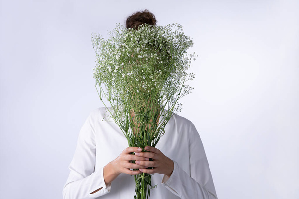 Women hiding her face behind baby breath flowers bouquet on a white background for valentines day - Foto, immagini