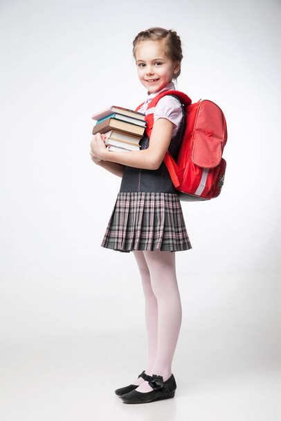 Happy little schoolgirl in uniform standing on white background - Foto, imagen