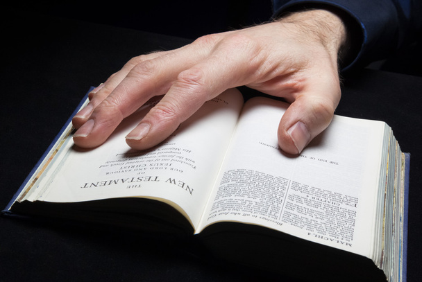 Mies, joka lukee Raamattua yhdellä kädellä
. - Valokuva, kuva