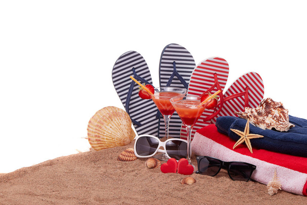 Beach accessories, seashells, sand, two glasses with cocktail and red hearts on white background.  Vacation  in warm countries, beach holiday and party. Honeymoon. Valentine's Day. Romantic travel - Valokuva, kuva