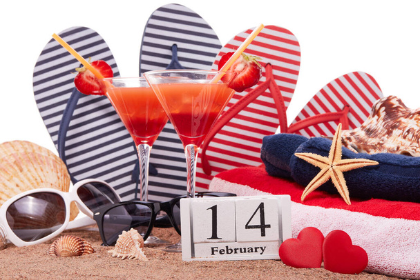 Beach accessories, seashells, sand, two glasses with cocktail, red hearts and calendar with date 14 february on white background. Beach party and  holiday . Valentine's Day background - Valokuva, kuva