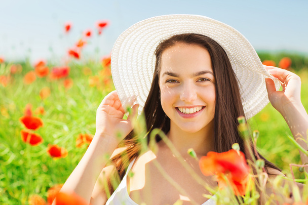 smiling young woman in straw hat on poppy field - Zdjęcie, obraz