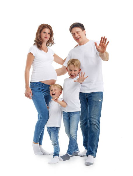 Happy parents: pregnant mother and father with lovely two sons are stand hugging, smiling and wave their hands, isolated on a white background. Happy friendly family. Concept of people and family - Photo, Image