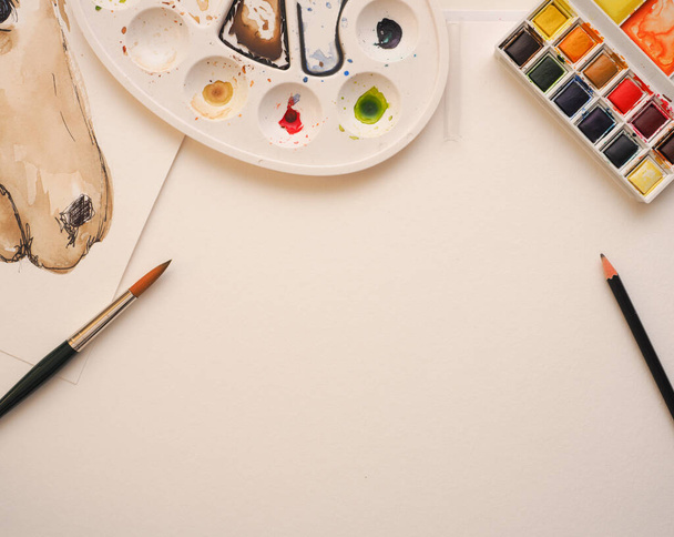 Blank watercolor paper sheet with painting utensils on a table, view from above - 写真・画像